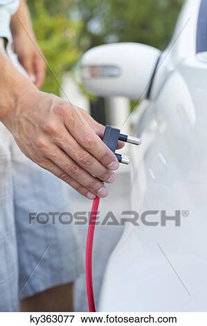 Mid section view of a mid adult man charging the electric car View Large Photo Image Stock Photo - Mid section view of a mid adult man charging the electric car. Fotosearch