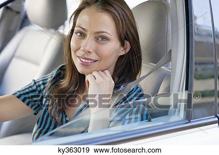 Stock Photo - Portrait of a beautiful young woman sitting at driver's seat. Fotosearch