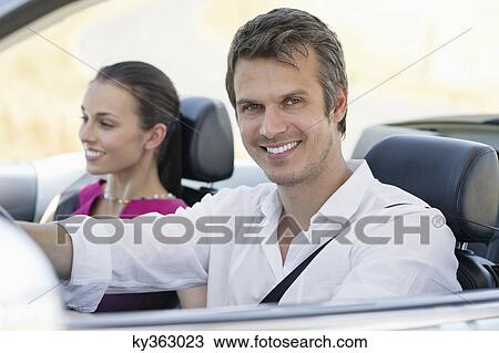 Stock Image - Portrait of a couple driving a convertible car. Fotosearch