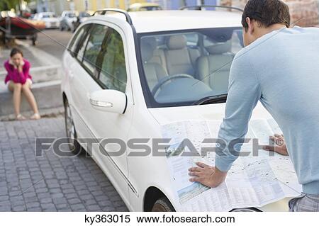 Rear view of a man looking at map on car with young woman sitting in the background View Large Photo Image Stock Photography - Rear view of a man looking at map on car with young woman sitting in the background. Fotosearch