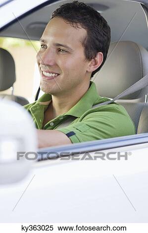 Smiling mid adult man driving a car View Large Photo Image Stock Photography - Smiling mid adult man driving a car. Fotosearch