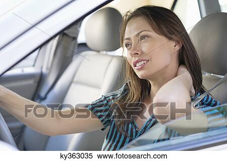 Tired young woman rubbing back of neck while driving a car View Large Photo Image Stock Photography - Tired young woman rubbing back of neck while driving a car. Fotosearch