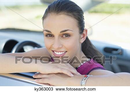 Young woman leaning on car window View Large Photo Image Stock Image - Young woman leaning on car window. Fotosearch