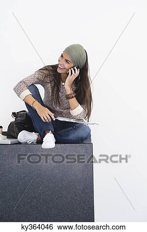 Stock Photograph - Beautiful woman talking over mobile phone against white background. Fotosearch