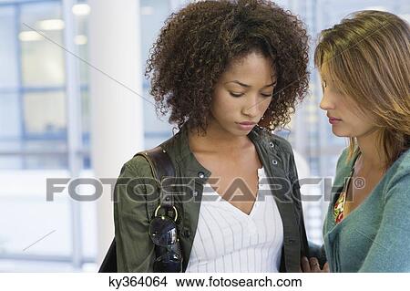 Caucasian woman consoling to an African American woman in university View Large Photo Image Picture - Caucasian woman consoling to an African American woman in university. Fotosearch