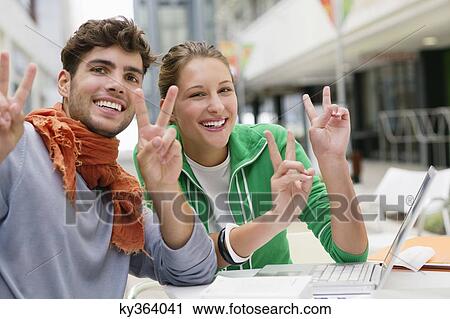 Portrait of friends gesturing peace while using laptop View Large Photo Image Stock Image - Portrait of friends gesturing peace while using laptop. Fotosearch