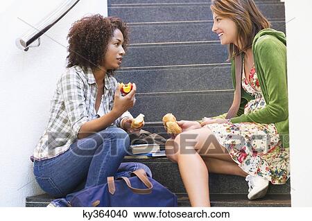 Side profile of university students eating food on stairs in university View Large Photo Image Stock Image - Side profile of university students eating food on stairs in university. Fotosearch