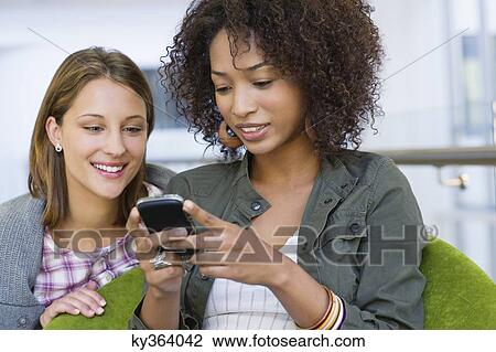 Smiling women using mobile phone in university View Large Photo Image Stock Image - Smiling women using mobile phone in university. Fotosearch