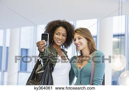 Two women taking photos of themselves View Large Photo Image Stock Image - Two women taking photos of themselves. Fotosearch