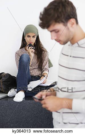 Two young people using mobile phones View Large Photo Image Stock Image - Two young people using mobile phones. Fotosearch