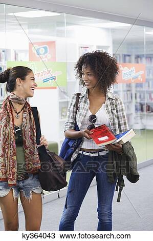 University students looking to each other in a library View Large Photo Image Stock Image - University students looking to each other in a library. Fotosearch