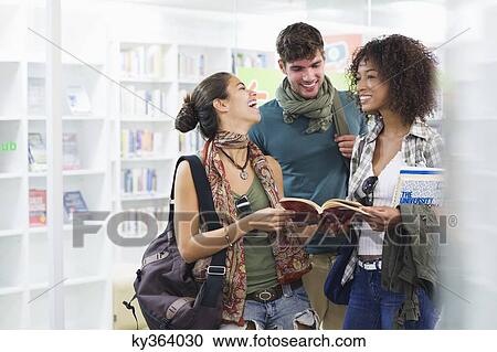 University students smiling while reading a book in a library View Large Photo Image Stock Image - University students smiling while reading a book in a library. Fotosearch