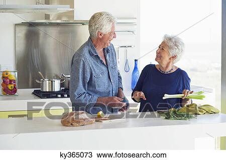 Happy senior couple preparing food in a domestic kitchen View Large Photo Image Stock Image - Happy senior couple preparing food in a domestic kitchen. Fotosearch