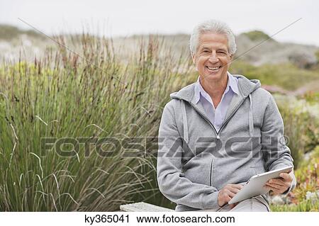 Happy senior man using a digital tablet View Large Photo Image Stock Image - Happy senior man using a digital tablet. Fotosearch