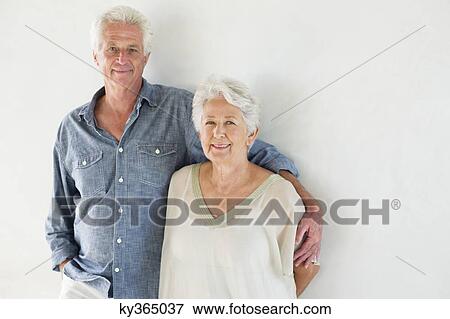 Portrait of a senior couple standing against a wall View Large Photo Image Stock Photo - Portrait of a senior couple standing against a wall. Fotosearch