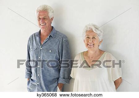Portrait of a senior couple standing against a wall View Large Photo Image Stock Photo - Portrait of a senior couple standing against a wall. Fotosearch