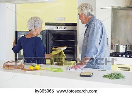 Senior couple baking food in an oven View Large Photo Image Stock Photography - Senior couple baking food in an oven. Fotosearch