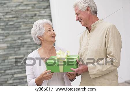Senior couple holding a gift box View Large Photo Image Stock Photo - Senior couple holding a gift box. Fotosearch