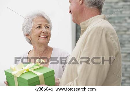 Senior couple holding a gift box View Large Photo Image Stock Photography - Senior couple holding a gift box. Fotosearch