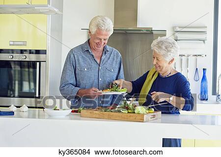 Senior couple preparing food at a domestic kitchen View Large Photo Image Picture - Senior couple preparing food at a domestic kitchen. Fotosearch