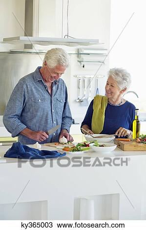 Senior couple preparing food at a domestic kitchen View Large Photo Image Stock Image - Senior couple preparing food at a domestic kitchen. Fotosearch