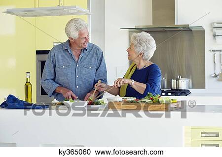 Senior couple preparing food at a domestic kitchen View Large Photo Image Stock Image - Senior couple preparing food at a domestic kitchen. Fotosearch