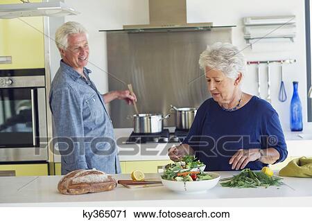 Senior couple preparing food in a domestic kitchen View Large Photo Image Stock Image - Senior couple preparing food in a domestic kitchen. Fotosearch