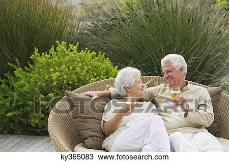 Stock Image - Senior couple toasting with wine. Fotosearch