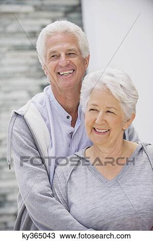 Senior man embracing his wife from behind View Large Photo Image Stock Image - Senior man embracing his wife from behind. Fotosearch