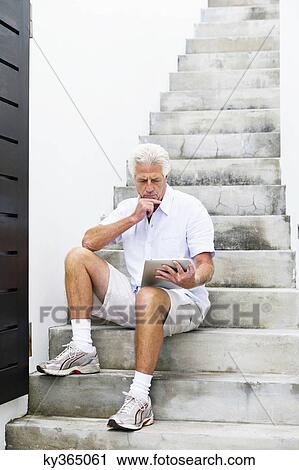 Senior man looking at digital tablet View Large Photo Image Stock Image - Senior man looking at digital tablet. Fotosearch