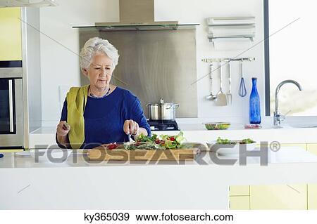 Senior woman cutting vegetable in a kitchen View Large Photo Image Stock Photo - Senior woman cutting vegetable in a kitchen. Fotosearch