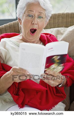 Stock Photography - Senior woman reading a magazine and looking surprised. Fotosearch