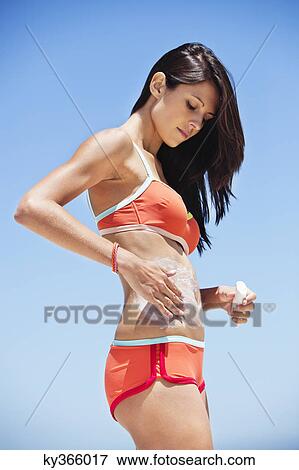 Woman applying suntan lotion on her body View Large Photo Image Stock Photo - Woman applying suntan lotion on her body. Fotosearch