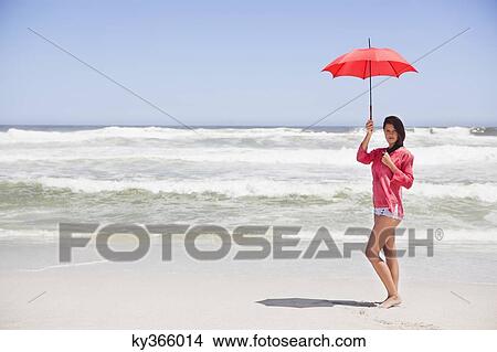 Picture - Woman standing on the beach with an umbrella. Fotosearch
