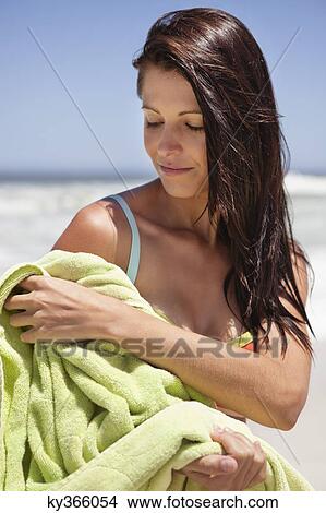 Woman wiping her body with towel on beach View Large Photo Image Picture - Woman wiping her body with towel on beach. Fotosearch