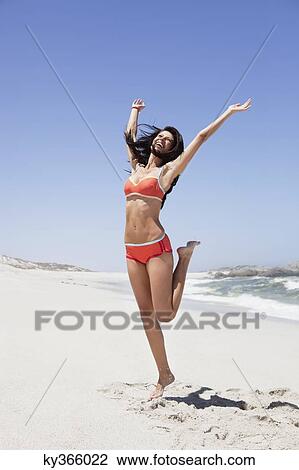 Young woman jumping on the beach View Large Photo Image Stock Image - Young woman jumping on the beach. Fotosearch