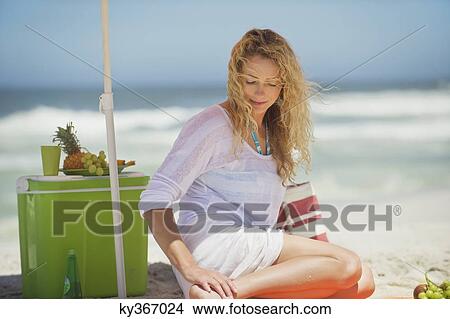 Picture - Beautiful woman sitting on the beach. Fotosearch