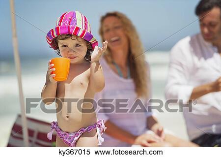 Girl drinking juice with her parents in the background View Large Photo Image Stock Photography - Girl drinking juice with her parents in the background. Fotosearch