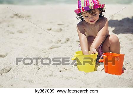Girl playing with sand on the beach View Large Photo Image Stock Photo - Girl playing with sand on the beach. Fotosearch