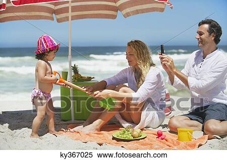 Stock Photography - Girl pulling shovel from mother on the beach. Fotosearch