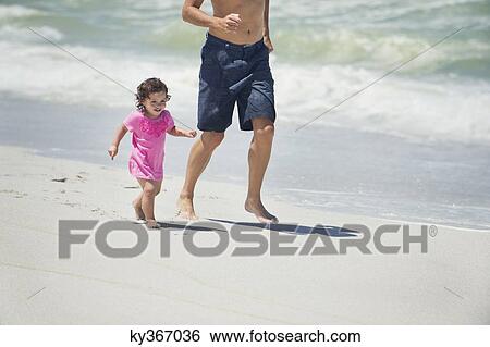 Stock Photograph - Man running with little daughter on the beach. Fotosearch