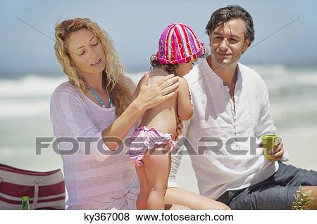 Stock Photo - Mother applying suntan lotion to her daughter's back on the beach. Fotosearch