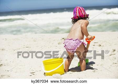 Rear view of a girl digging with a sand shovel on the beach View Large Photo Image Picture - Rear view of a girl digging with a sand shovel on the beach. Fotosearch
