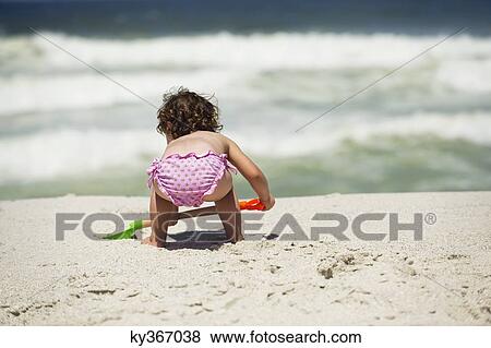Rear view of a girl digging with a sand shovel on the beach View Large Photo Image Stock Photo - Rear view of a girl digging with a sand shovel on the beach. Fotosearch