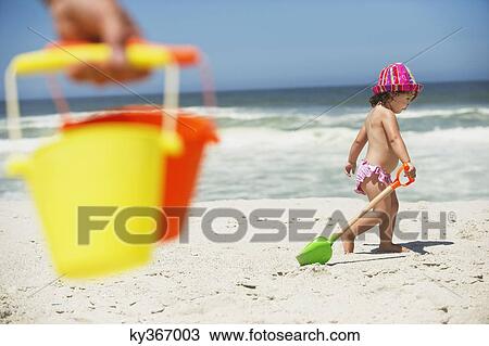 Side profile of a girl walking with sand shovel on the beach View Large Photo Image Stock Image - Side profile of a girl walking with sand shovel on the beach. Fotosearch