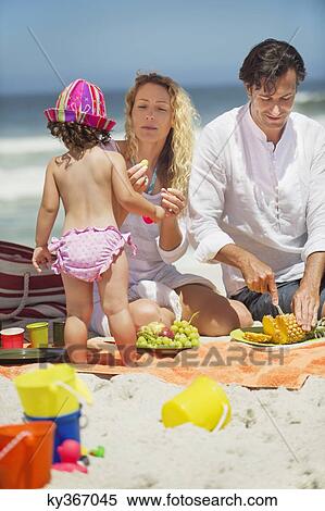 Woman feeding fruits to her daughter on the beach View Large Photo Image Stock Photography - Woman feeding fruits to her daughter on the beach. Fotosearch