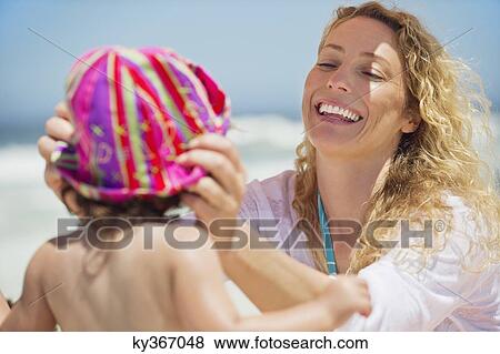 Stock Photo - Woman putting a cap on her daughter head. Fotosearch