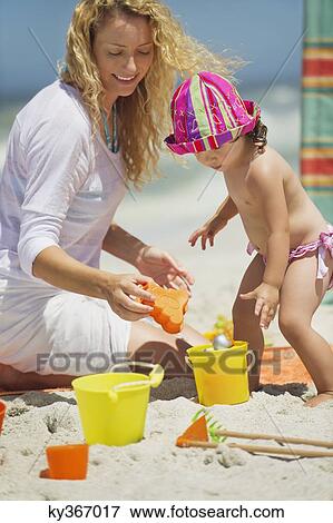 Woman with her daughter playing with pail and shovel on the beach View Large Photo Image Stock Photo - Woman with her daughter playing with pail and shovel on the beach. Fotosearch