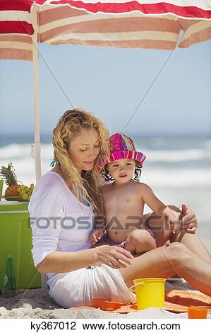 Woman with her daughter sitting on the beach View Large Photo Image Stock Image - Woman with her daughter sitting on the beach. Fotosearch