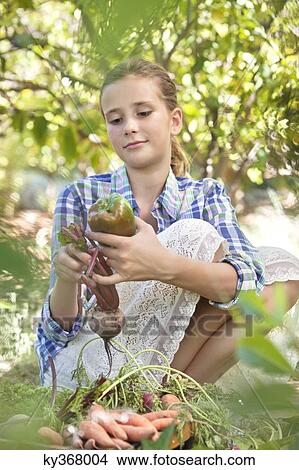 Girl choosing vegetables from a crate View Large Photo Image Picture - Girl choosing vegetables from a crate. Fotosearch